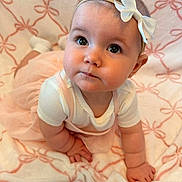 Lainey is registered to the contest to win money with this photo: baby, infant, child, girl, crawling, blanket, bow, headband, pink, white, clothing, cute, indoors, soft, pattern, portrait, curious, face, closeup, hands