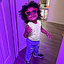 Maliyah is registered to the contest to win money with this photo: child, curly_hair, cute, door, fashion, happy, heart_shaped_glasses, home_interior, indoor, person, playful_pose, printed_pants, purple_light, smiling, sneakers, sunglasses, toddler, wall, wood_floor, yellow_tank_top