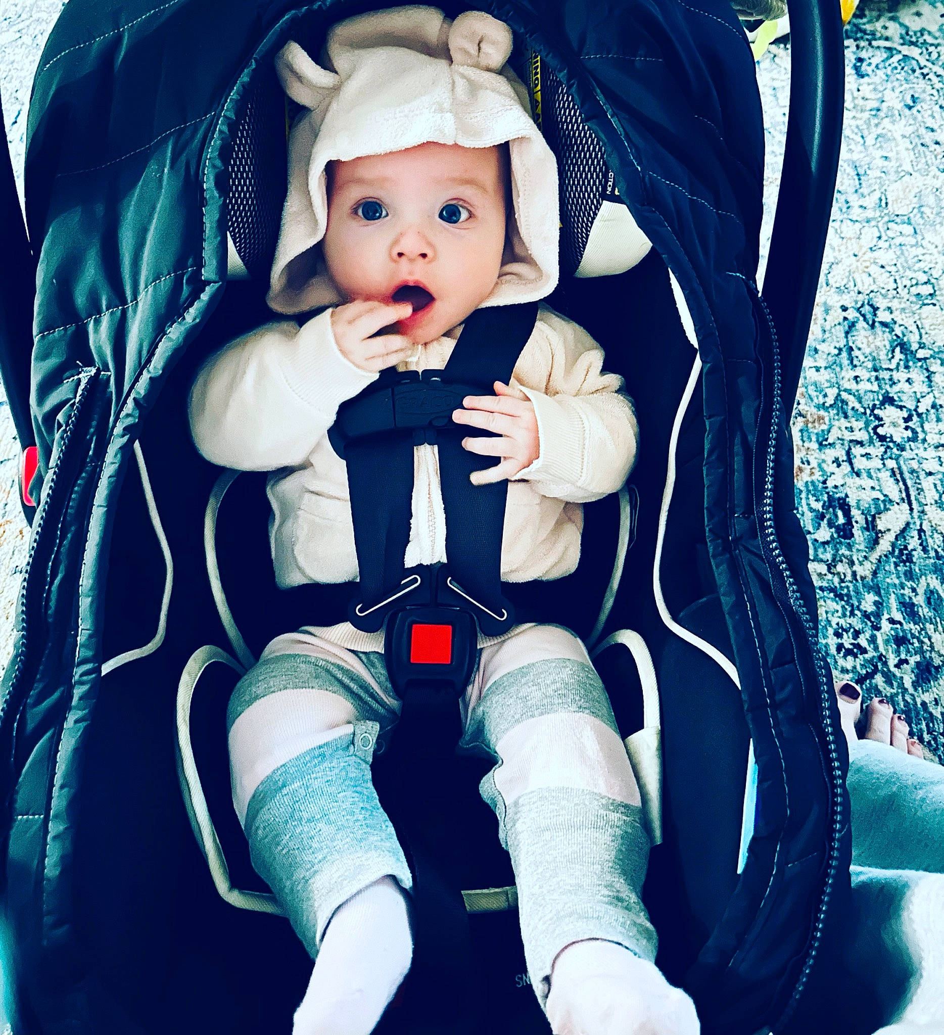 Raegan is registered to the contest to win money with this photo: arm, baby, baby_carriage, baby_products, baby_toddler_clothing, comfort, doll, electric_blue, eye, hat, headwear, human_body, human_leg, knee, lap, person, sitting, sleeve, sock, surprise