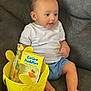 Ares joined the competition — help win amazing prizes! baby, child, couch, gray, white_shirt, blue_shorts, yellow_bucket, easter_buddies, candy, easter, duck_candy, toy, sitting, indoors, smiling, cute, foot, hand, face, happy
