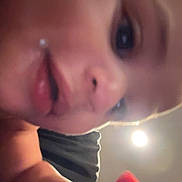 Ares is registered to the contest to win money with this photo: baby, close_up, face, hand, curious, indoor, skin, expression, child, young, person, light, blur, mouth, nose, eye, cheek, fingertip, background, focus