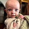 baby, blanket, child, close_up, clothing, cozy, eyes, face, head, home, indoor, infant, looking_at_camera, person, photography, portrait, soft_focus, swaddle, warm_lighting, wide_eyed