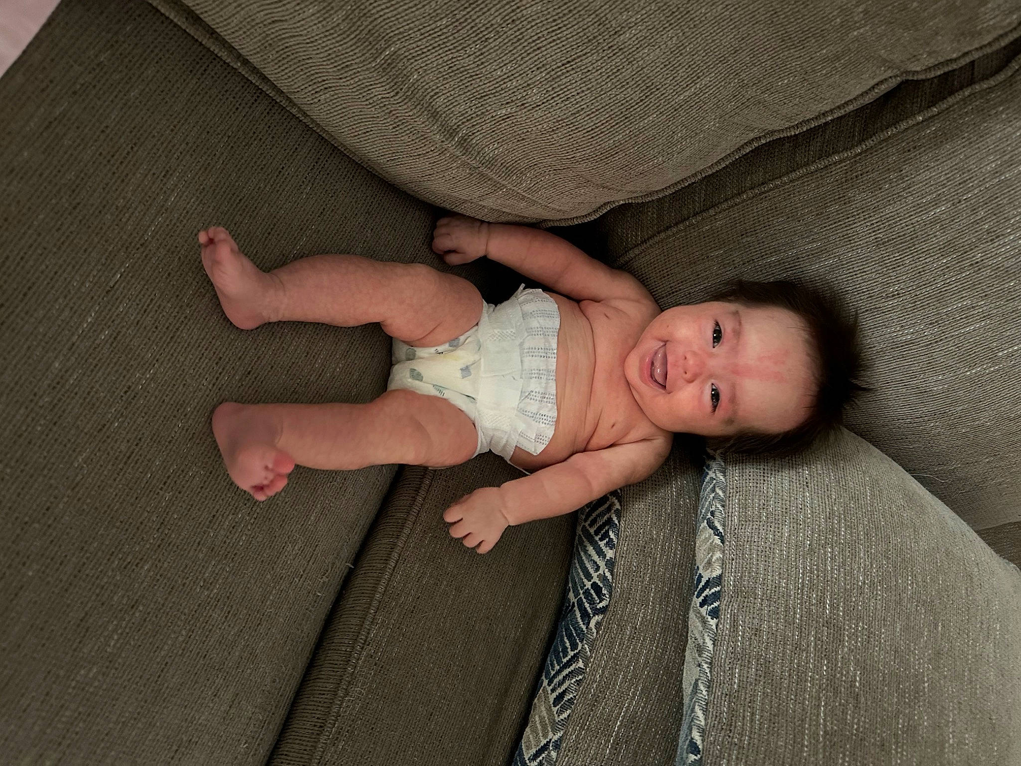 Mia is registered to the contest to win money with this photo: baby, baby_toddler_clothing, cheek, child, comfort, finger, foot, head, human_body, human_leg, joy, linens, pattern, person, sitting, skin, sleeve, sock, textile, thumb