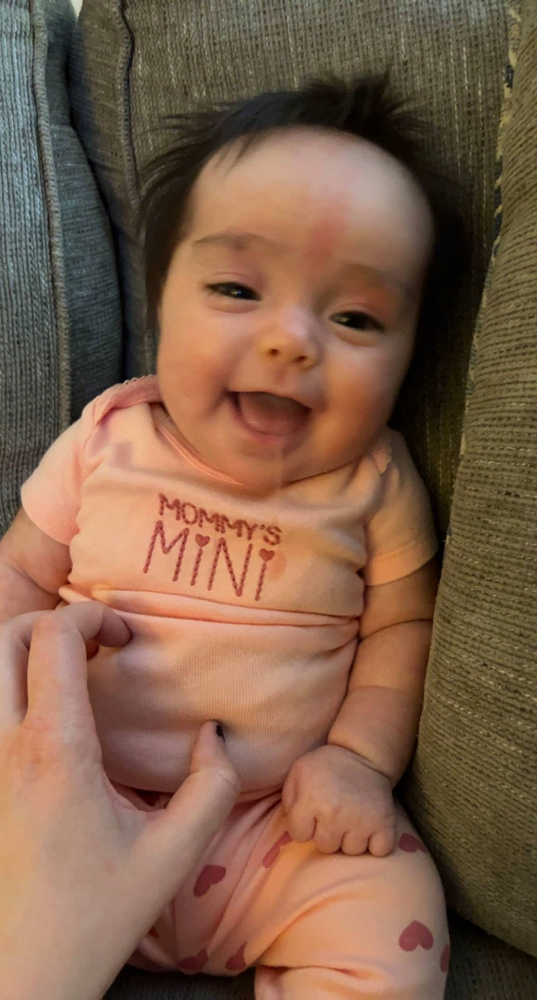 Mia is registered to the contest to win money with this photo: baby, baby_toddler_clothing, cheek, chin, comfort, face, finger, gesture, hand, happy, lip, mouth, neck, nose, person, product, skin, sleeve, smile, stomach