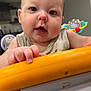 Eli joined the competition — help win amazing prizes! baby, infant, child, face, hand, toy, orange, white, indoor, curious, closeup, person, young_child, expression, candid, playing, background, kitchen, furniture, exploring