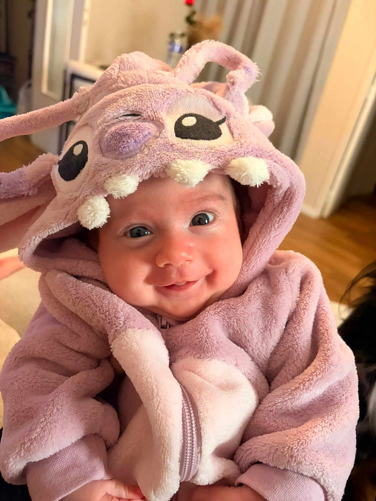 Isadora participe au concours pour gagner de l'argent avec cette photo : baby, child, smiling, hood, costume, purple, plush, cute, indoor, person, face, eyes, teeth, soft, happy, infant, clothing, warm, portrait, babywearing