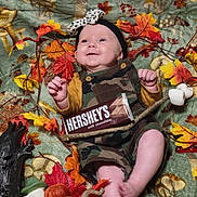 Berkley is registered to the contest to win money with this photo: baby, child, smiling, camo_overalls, headband, autumn_leaves, pumpkin, chocolate_bar, blanket, fall_theme, decorations, marshmallows, stick, mushroom_pattern, orange, yellow, red, cute, happy, indoors