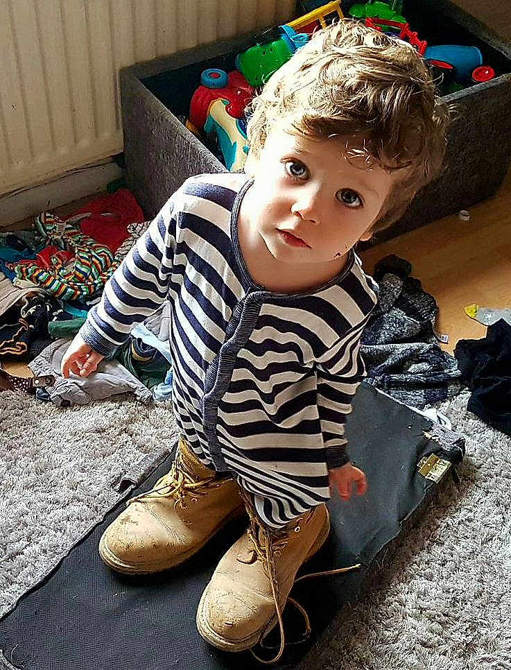 Kian joined the competition — help win amazing prizes! toddler, child, boots, striped_clothing, messy_room, toys, carpet, curious, indoor, clothes, floor, young_child, portrait, looking_up, casual, playtime, home, person, footwear, expression