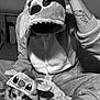 person, dog, animal_costume, plush, onesie, hood, hand, tattoo, socks, bed, blanket, indoor, black_and_white, cute, pet, matching_outfits, portrait, seated, face, cozy