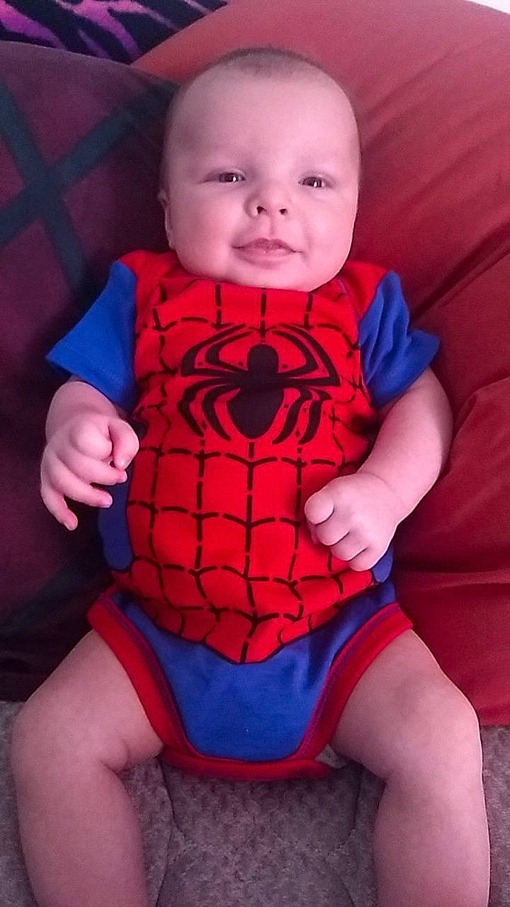 Gray is registered to the contest to win money with this photo: baby, baby_products, baby_toddler_clothing, blue, cheek, child, fictional_character, mouth, pattern, person, red, sitting, smile, spider_man, superhero, superman, toddler
