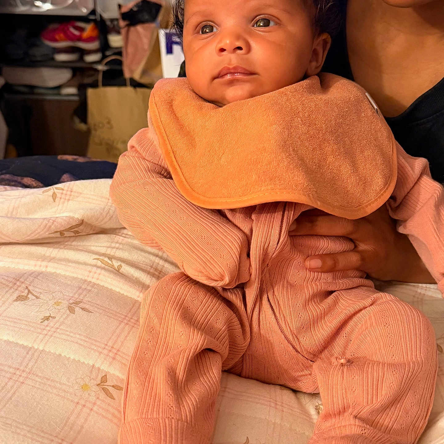 Kouture joined the competition — help win amazing prizes! baby, infant, child, portrait, sitting, peach_outfit, bib, curly_hair, wide_eyes, calm, adult, caregiver, holding, indoors, bed, bedding, home, close_up, family, photography