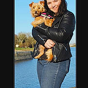 Pèpette participe au concours pour gagner de l'argent avec cette photo : animal, blue_sky, canine, casual_clothing, daylight, dog, happy, holding, jeans, leather_jacket, nature, outdoor, person, pet, river, service_dog, small_dog, smiling, trees, water