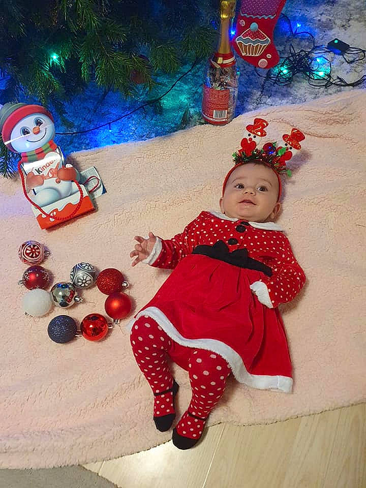 Daria participe au concours pour gagner de l'argent avec cette photo : baby_toddler_clothing, child, christmas, christmas_decoration, christmas_ornament, christmas_tree, event, facial_expression, fun, happy, head, holiday, holiday_ornament, human_body, organ, person, red, snow, toddler, tree