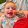 baby, blanket, bodypart, clothing, dress, face, grass, happy, head, laughing, mouth, person, photography, plant, portrait, skin, smile, t_shirt, tattoo, teeth