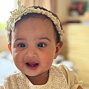 Meera joined the competition — help win amazing prizes! baby, child, face, smile, headband, flower, lace, dress, indoor, portrait, cute, infant, young_child, happy, skin, eyes, mouth, person, apparel, headwear
