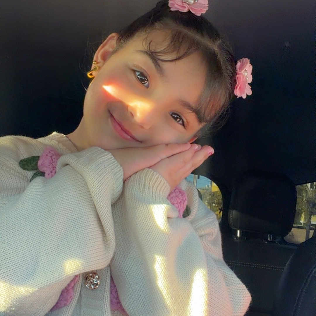 Maribel joined the competition — help win amazing prizes! child, girl, smiling, portrait, car, car_interior, flower_hair_clips, hair_accessories, sweater, knitwear, hands, posing, sunlight, warm_lighting, face, eyes, indoors, happy, fashion, cute