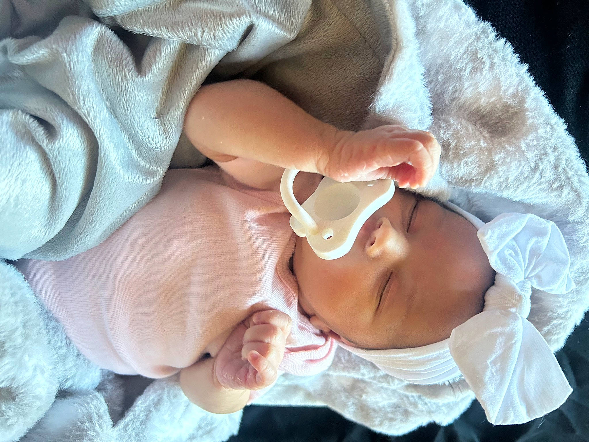 River is registered to the contest to win money with this photo: arm, baby, baby_products, baby_toddler_clothing, cheek, comfort, dress, eyelash, finger, gesture, hand, human_body, mouth, nail, nose, person, skin, sleeve, textile, thumb