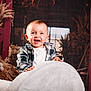 baby, background, barn, child, cute, decor, dried_flowers, furniture, hands, happy, indoors, natural_light, person, plaid_shirt, portrait, rustic, smiling, white_chair, wooden_door, young