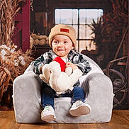 Soan participe au concours pour gagner de l'argent avec cette photo : armchair, beanie, casual_clothing, child, cozy, cute, dried_flowers, happy, homedecor, indoor, jeans, plaid_shirt, plush, portrait, rustic, smiling, stuffed_toy, toddler, white_shoes, wooden_floor