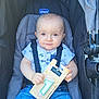 baby, child, stroller, seatbelt, blue_jeans, white_shirt, face, hand, number_1_candle, package, smile, sitting, outdoor, sunlight, cute, infant, closeup, birthday, festive, person