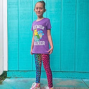 Paislea is registered to the contest to win money with this photo: child, standing, purple_shirt, pokemon, trainer, leggings, leopard_print, colorful_shoes, high_tops, outdoor, concrete_floor, blue_wall, casual_clothing, smiling, young_girl, fashion, portrait, vibrant_colors, playful, confident