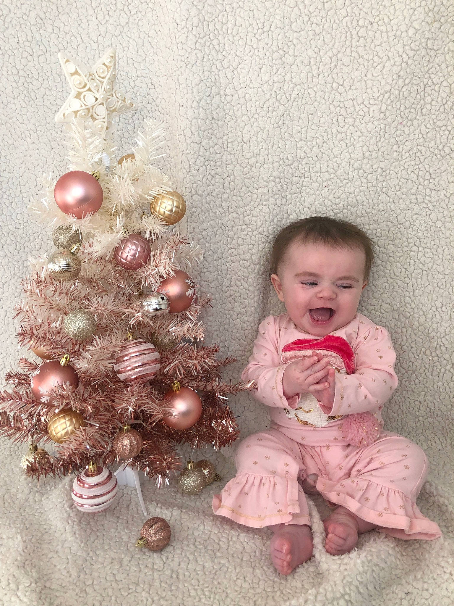 Scarlett is registered to the contest to win money with this photo: baby, baby_toddler_clothing, christmas_decoration, christmas_ornament, christmas_tree, event, evergreen, flooring, happy, holiday, holiday_ornament, human_body, ornament, person, pink, plant, sleeve, smile, toddler, tree