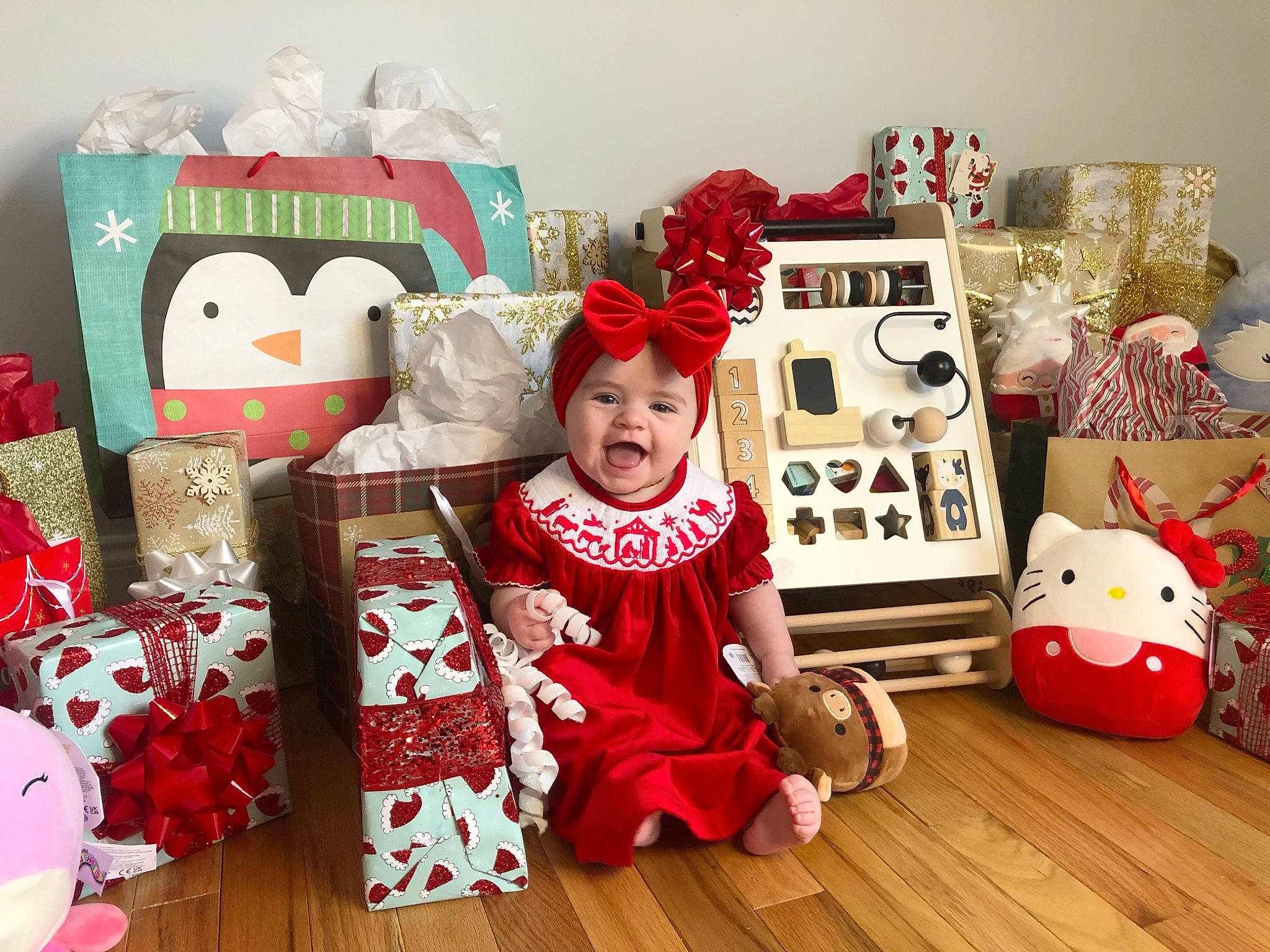 Scarlett is registered to the contest to win money with this photo: baby_toddler_clothing, carmine, child, christmas, christmas_eve, christmas_stocking, event, flooring, happy, headwear, holiday, person, red, room, shelf, smile, stuffed_toy, toddler, toy, white