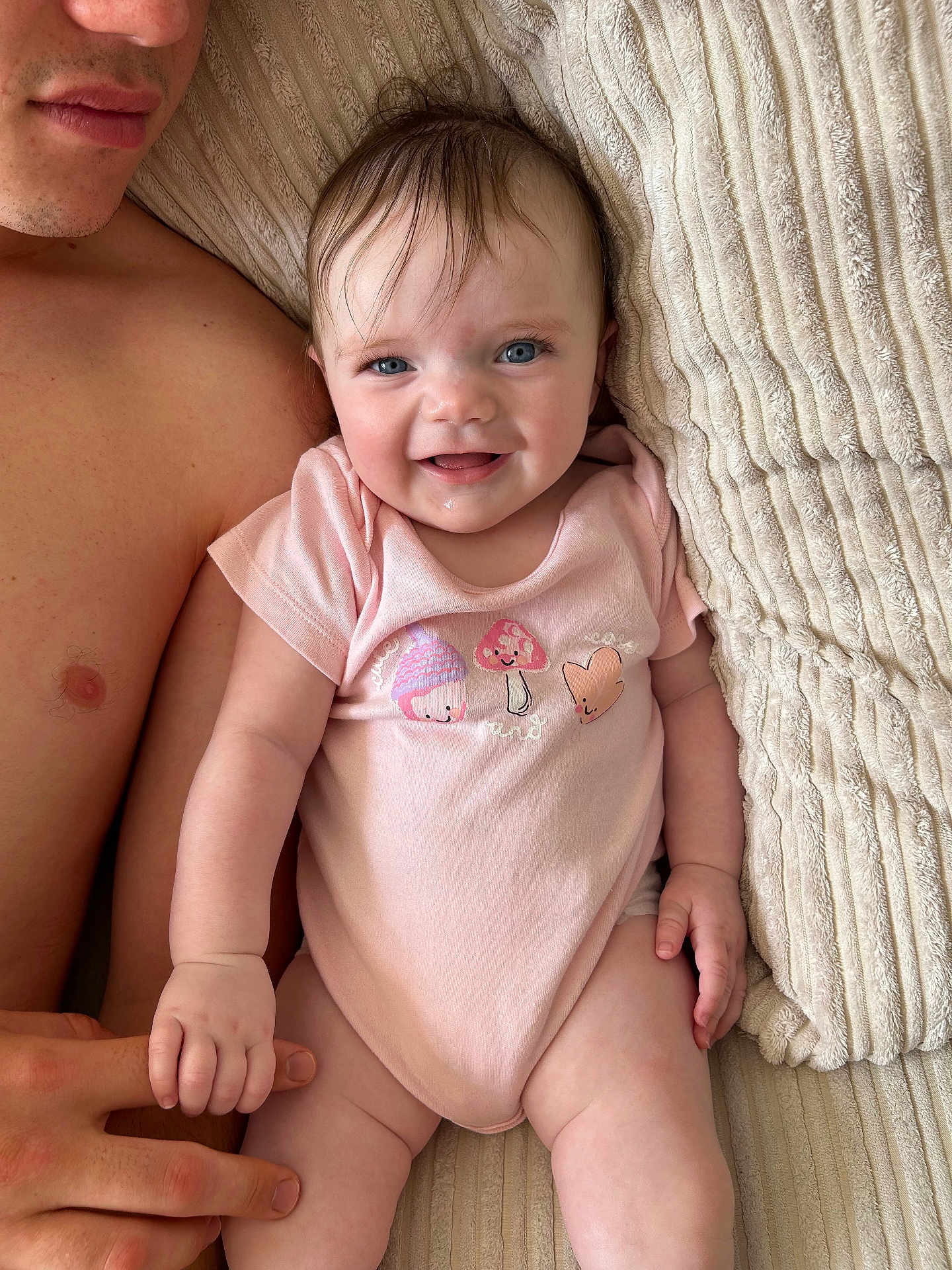 Madelyn joined the competition — help win amazing prizes! baby, infant, child, person, smiling, holding_hand, pink_onesie, mushroom_print, heart_print, blanket, textured_blanket, bare_chest, adult_hand, skin, blue_eyes, happy, lying_down, close_up, cute, indoors