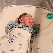 Braxton is registered to the contest to win money with this photo: newborn, baby, infant, sleeping, smiling, face, portrait, blanket, swaddle, crib, bassinet, pacifier, mitten, clothing, indoor, nursery, cozy, lying_down, bed, photography