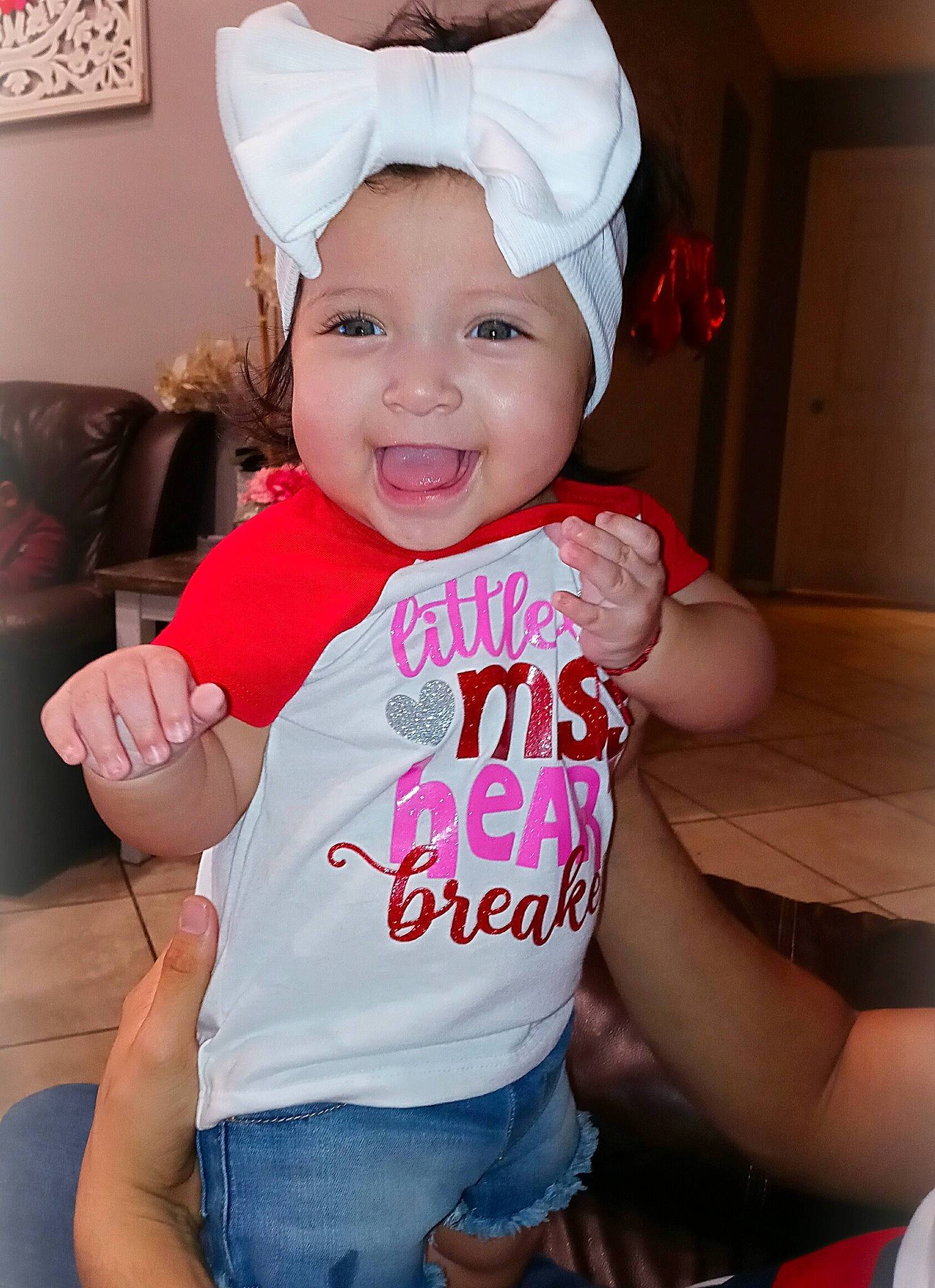 Dariana is registered to the contest to win money with this photo: arm, baby, baby_toddler_clothing, chair, child, clothing, costume_hat, fun, happy, head, headwear, human_body, joy, mouth, person, picture_frame, pink, sleeve, smile, t_shirt