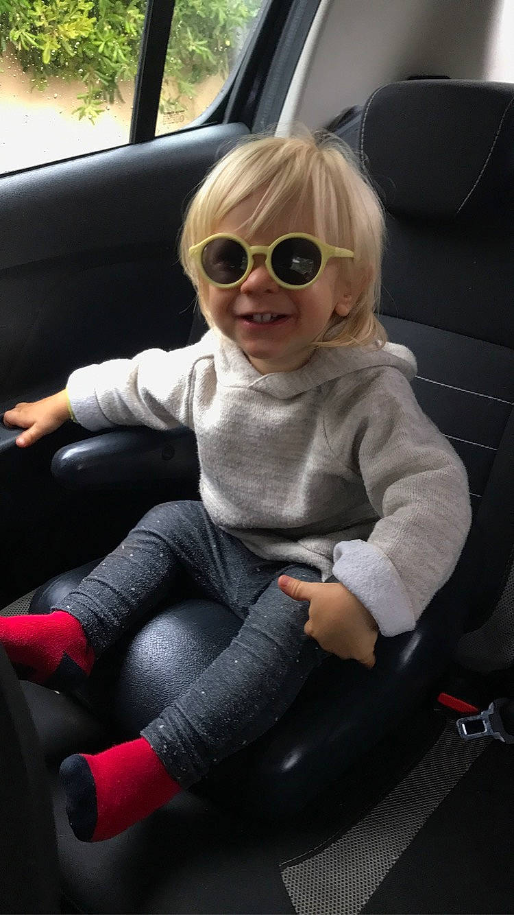 Axel participe au concours pour gagner de l'argent avec cette photo : automotive_design, automotive_exterior, car_seat, car_seat_cover, comfort, eyewear, glasses, goggles, head_restraint, jeans, joy, motor_vehicle, person, seat_belt, smile, steering_part, steering_wheel, sunglasses, thigh, toddler