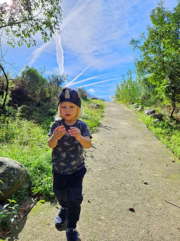 Axel a rejoint le concours — aidez-le/la à gagner de superbes lots ! adventure, electric_blue, forest, grass, grassland, headwear, hill, landscape, leisure, mountain, natural_landscape, people_in_nature, person, plant, recreation, road, rural_area, sky, toddler, trail
