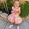 Elliana is registered to the contest to win money with this photo: toddler, child, girl, dress, floral_pattern, pink_bow, white_shoes, outdoor, garden, greenery, plants, concrete, wall, happy, smiling, standing, curly_hair, sunlight, portrait, cute