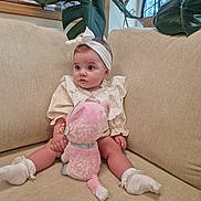 Marnie is registered to the contest to win money with this photo: baby, child, infant, stuffed_animal, plush_toy, couch, sofa, headband, socks, plant, leaves, indoor, cute, seated, clothing, soft_toy, home, portrait, young_child, furniture