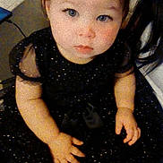 Isabella is registered to the contest to win money with this photo: toddler, child, baby, dress, black_dress, white_tights, blue_eyes, indoor, sitting, curious, person, face, hands, short_hair, floor, water_bottle, table, background, cute, portrait