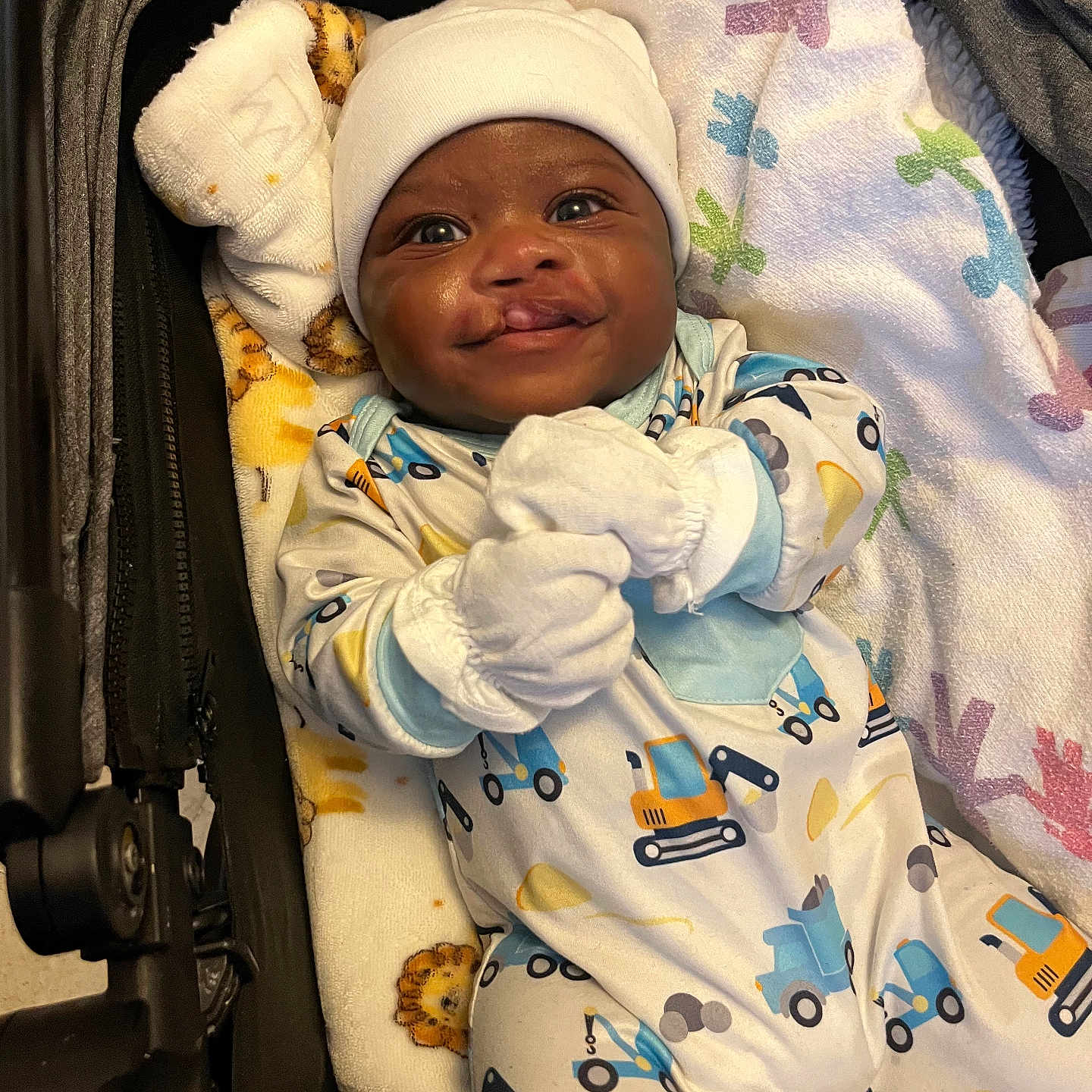 Ty'Aire Avant is registered to the contest to win money with this photo: baby, infant, smiling, face, onesie, mittens, hat, blanket, stroller, child, cute, happy, indoors, person, clothing, portrait, lying_down, baby_bedding, toddler, newborn
