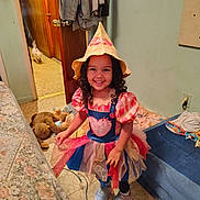Dymond joined the competition — help win amazing prizes! child, girl, smiling, costume, hat, dress, tutu, curly_hair, indoor, bedroom, bed, stuffed_animal, toy, shoes, sneakers, doorway, dog, floor, wall, electrical_outlet