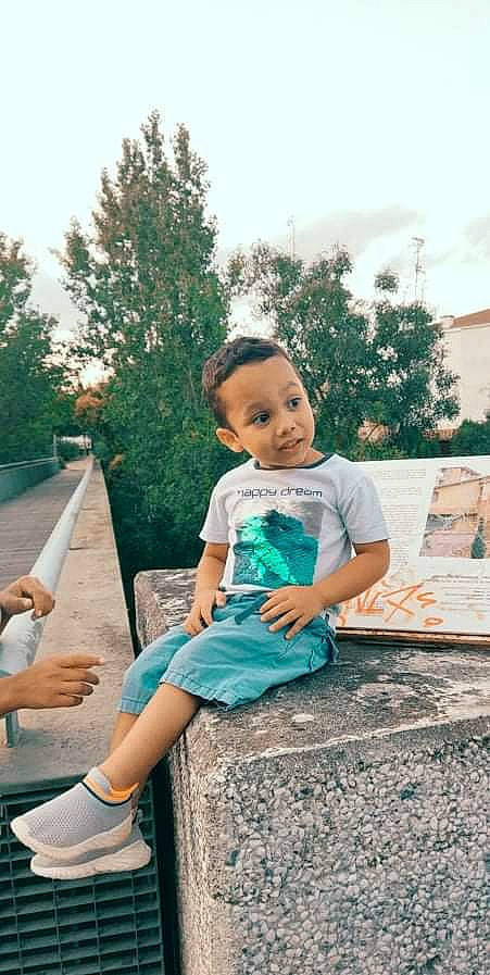 Anthonio participe au concours pour gagner de l'argent avec cette photo : boot, child, flash_photography, fun, grass, happy, human_leg, leisure, people_in_nature, person, plant, recreation, sandal, shorts, sitting, sky, t_shirt, thigh, toddler, tree