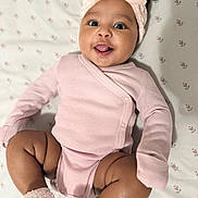 Ivonne joined the competition — help win amazing prizes! baby, infant, pink_clothing, headband, smiling, tongue_out, cute, lying_down, blanket, pattern, floral, soft_texture, cozy, happy, adorable, child, skin, face, legs, footwear