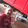 baby, child, indoor, red_shirt, text_on_clothing, metal_cabinet, floor, chair, foot, person, blur, casual, messy_background, infant, sitting, clothing, young_child, portrait, home, cute