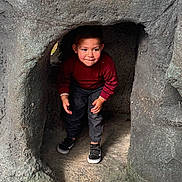 Andrea participe au concours pour gagner de l'argent avec cette photo : child, toddler, boy, face, red_sweater, jeans, sneakers, crouching, rock, cave, playground, peekaboo, expression, hands, portrait, adventure, curious, smile, clothing, shoe