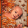 Asher is registered to the contest to win money with this photo: baby, blanket, cheerleader, closeup, cute, decorative_border, face, football, football_helmet, frame, hand, head, infant, lying_down, orange, pom_poms, portrait, smiling, sports_theme, white