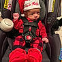 baby, booties, car_seat, carrier, child, christmas, cute, expression, festive, holiday, indoors, infant, newborn, person, plaid_pants, red_clothing, santa_hat, seatbelt, small, straps