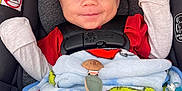 Asher is registered to the contest to win money with this photo: baby, baby_accessories, blanket, car_seat, child, closeup, comfort, cozy, cute, face, happy, indoor, infant, mittens, newborn, pacifier, portrait, red_clothing, safety_harness, smiling