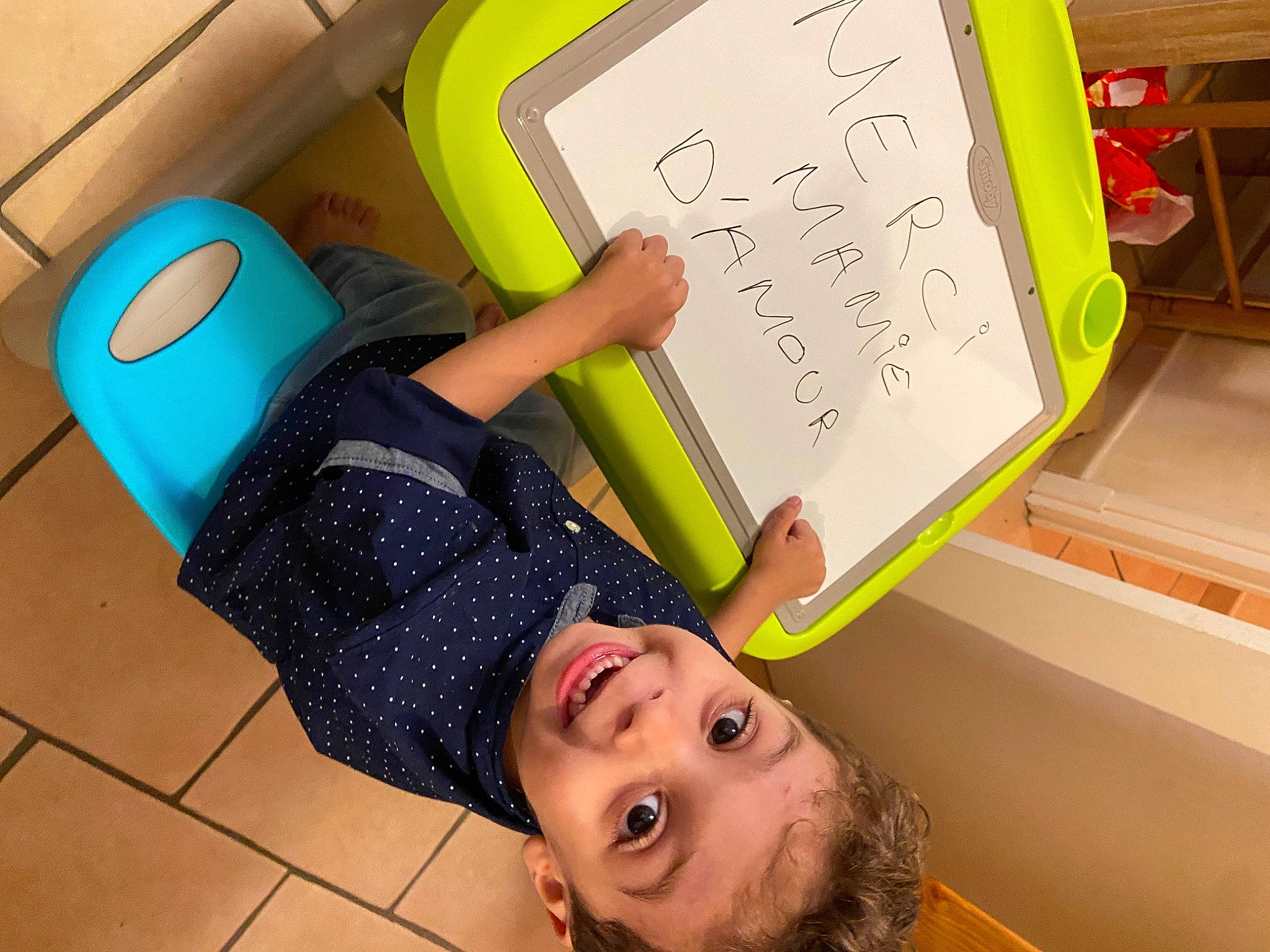 Adem a rejoint le concours — aidez-le/la à gagner de superbes lots ! chair, child, finger, flooring, font, fun, green, handwriting, knee, leisure, office_supplies, person, room, snapshot, stationery, t_shirt, thigh, toddler, writing, writing_instrument_accessory