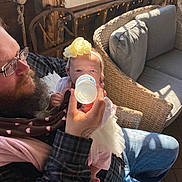 Avia is registered to the contest to win money with this photo: baby, beard, bottle, cozy, cushion, dress, family, feeding, glasses, headband, indoor, jeans, man, plaid_shirt, sunlight, tattoo, tulle, wicker_chair, window, yellow