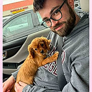 Charlie joined the competition — help win amazing prizes! beard, brown_dog, car_interior, casual_clothing, cute, dog, glasses, hoodie, indoor, man, parking_lot, person, pet, portrait, puppy, rain, seatbelt, smile, vehicle, window