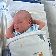 Noah is registered to the contest to win money with this photo: newborn, baby, sleeping, blanket, dinosaur, hospital, bassinet, infant, cute, peaceful, swaddled, child, resting, soft, toddler, blue_clothing, face, head, arm, indoors