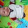 baby, smiling, play_mat, colorful, animal_print, flower_print, shirt, striped_sleeves, yellow_pants, child, infant, happy, lying_down, cute, face, dimples, indoors, clothing, person, bright
