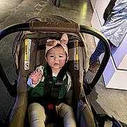 Brissa joined the competition — help win amazing prizes! baby, car_seat, bow, indoor, child, toddler, person, floor, clothing, footwear, concrete, curious, reaching, seatbelt, headband, walking, background, jeans, jacket, shoes